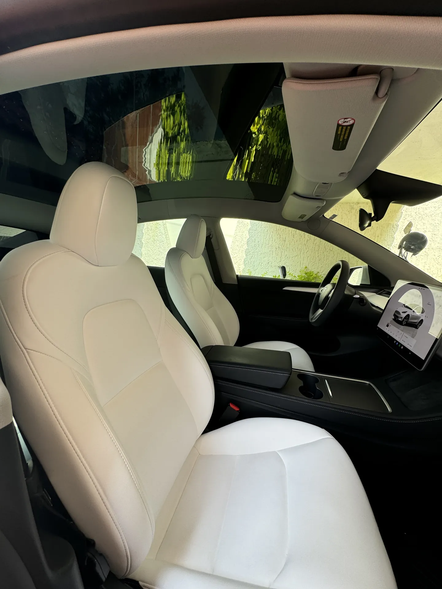 Interior de un auto con asientos blancos y cristales polarizados vistos desde dentro.