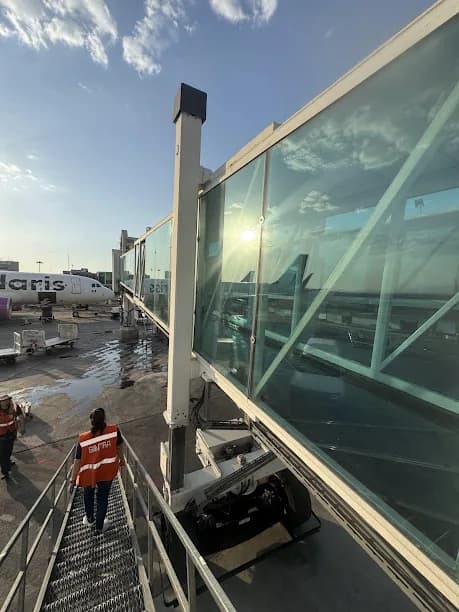 Pasarela acristalada con vista a la plataforma del aeropuerto, trabajo documentado por HIGHTECH.