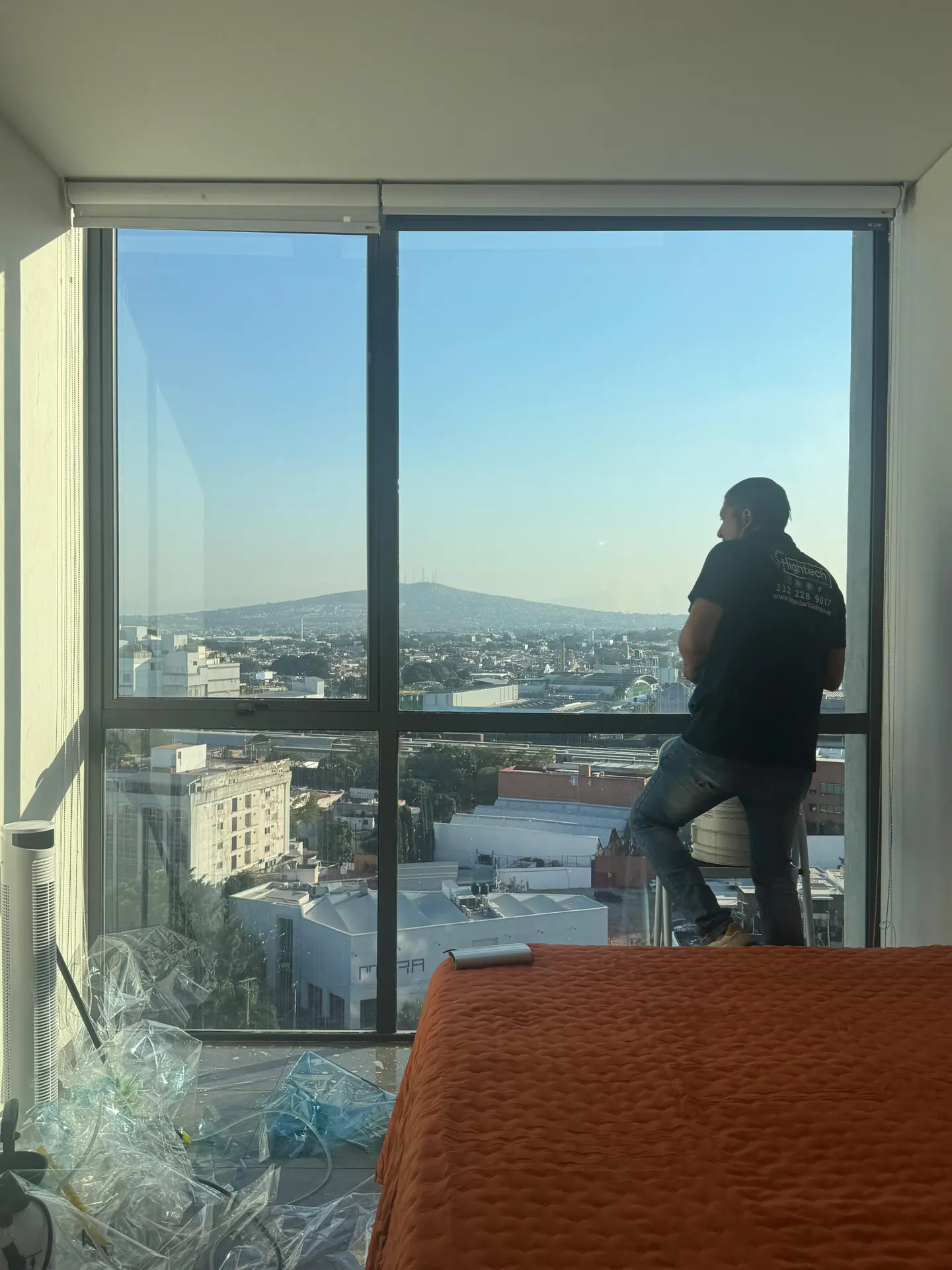 Instalador aplicando película en un ventanal con vista a la ciudad, trabajo documentado por HIGHTECH.