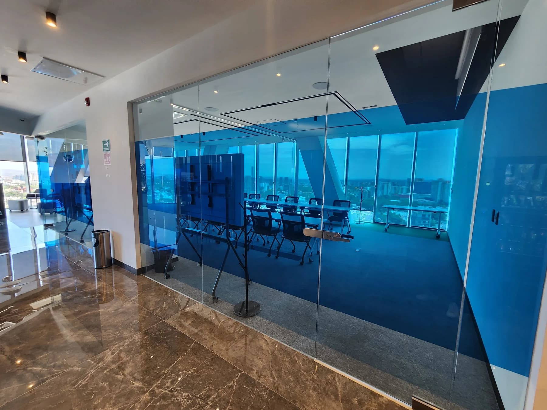 Oficina con divisiones de cristal y ventanales en un proyecto comercial documentado por HIGHTECH.