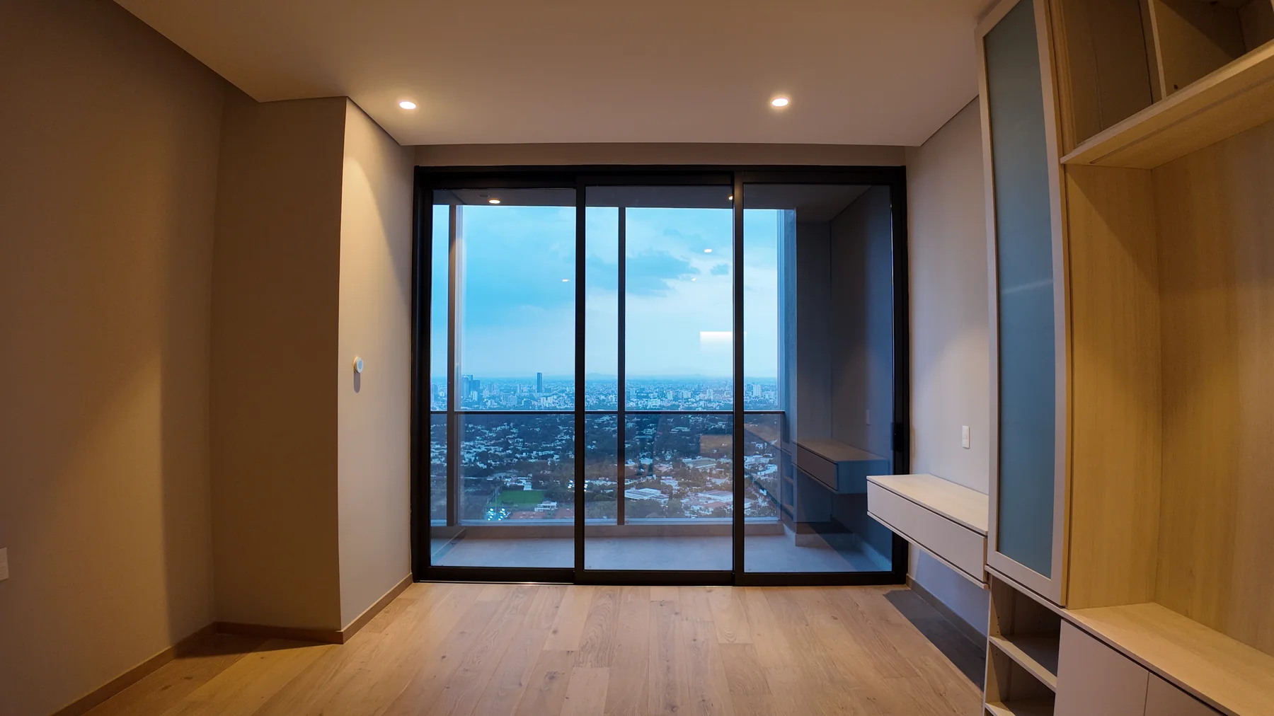 Interior de una casa con ventanal de piso a techo y vista urbana, en un proyecto residencial de HIGHTECH.
